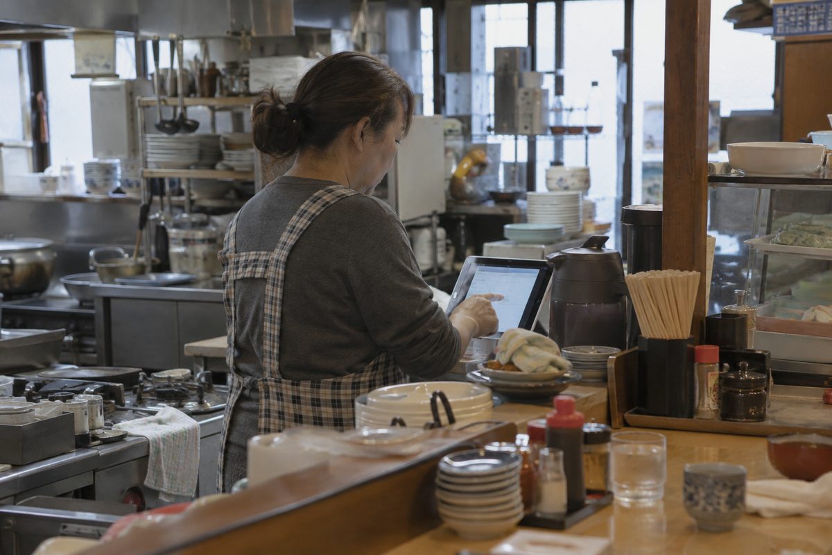 カウンターでタブレットを確認する店主